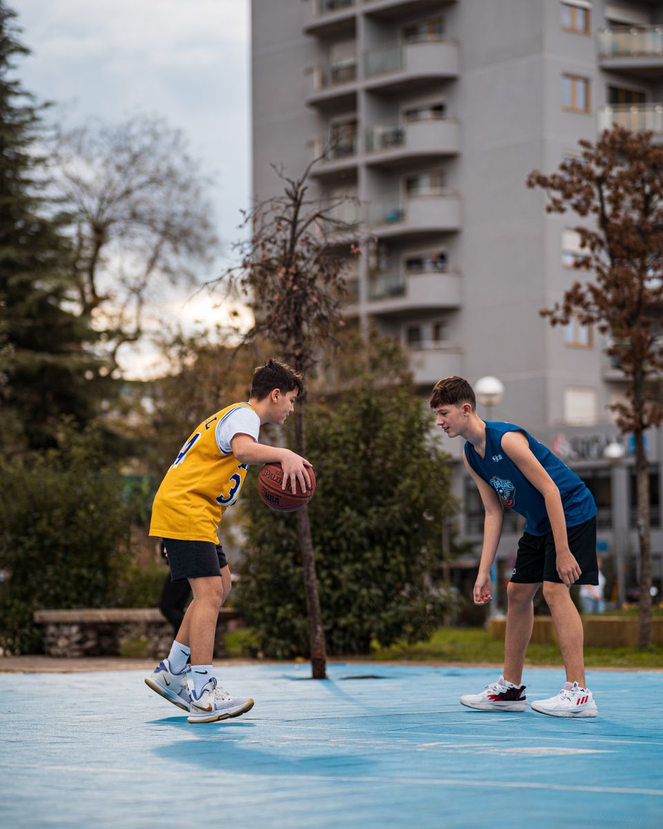 Two teenagers playing basketball on an outdoor court